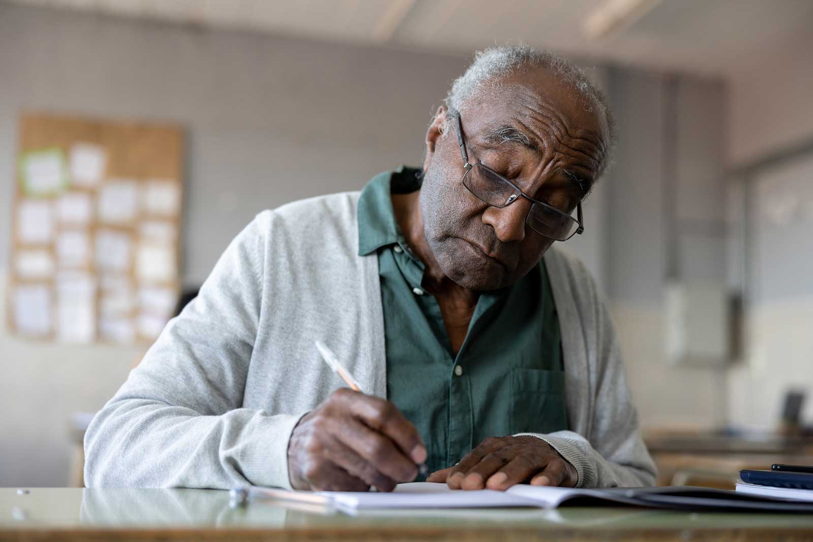 Senior seated at table writing in notebook